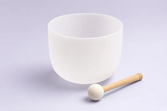 A frosted quartz crystal singing bowl with its mallet